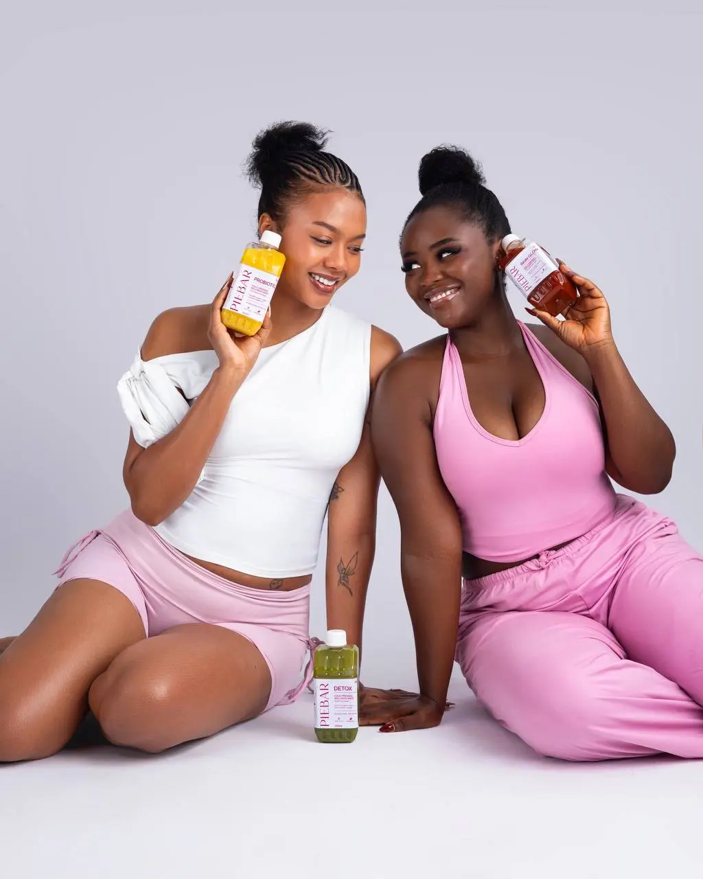 Two models presenting Pie Bar juice bottles